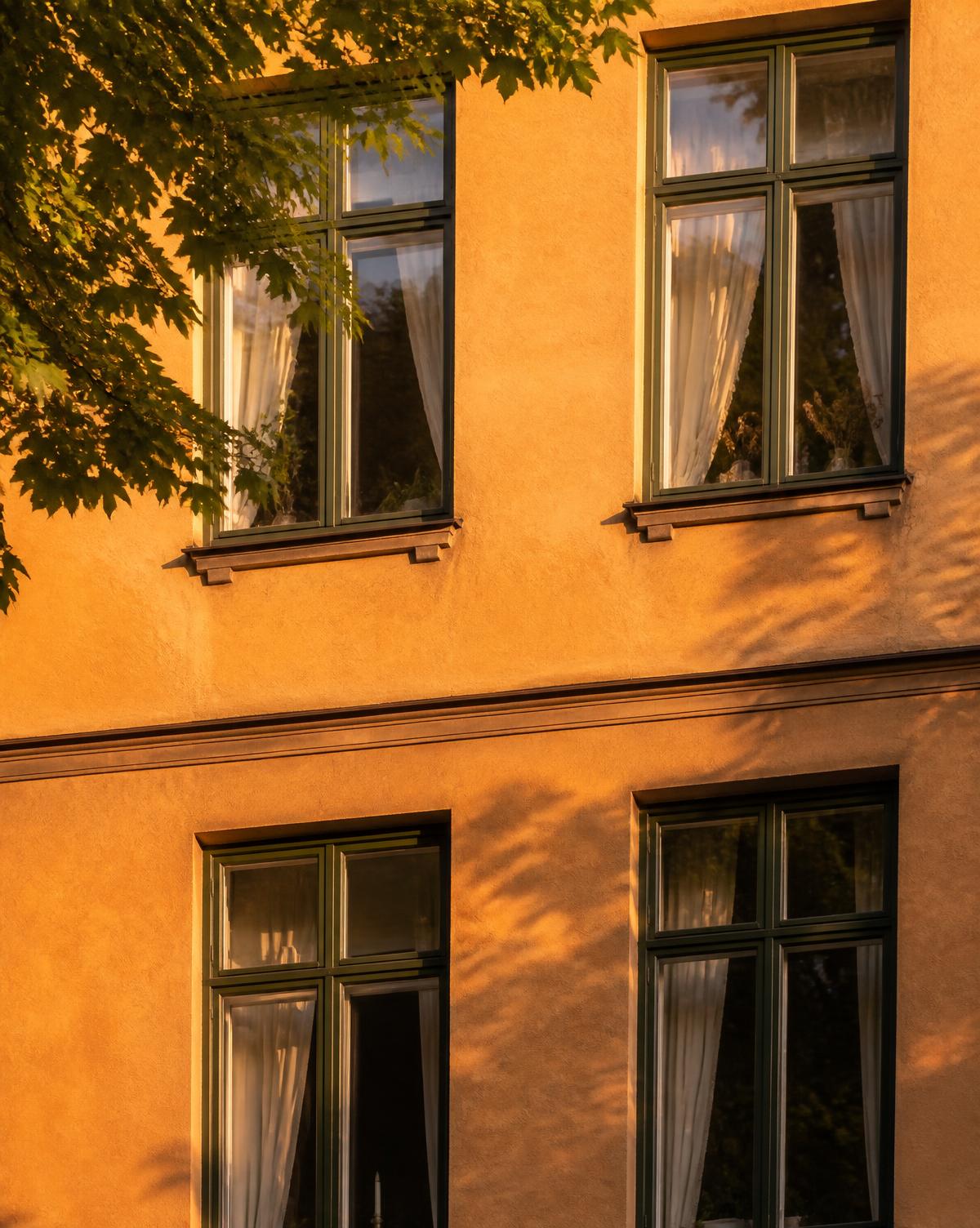 Varm ockrafasad med spröjsade fönster i Stockholms innerstad